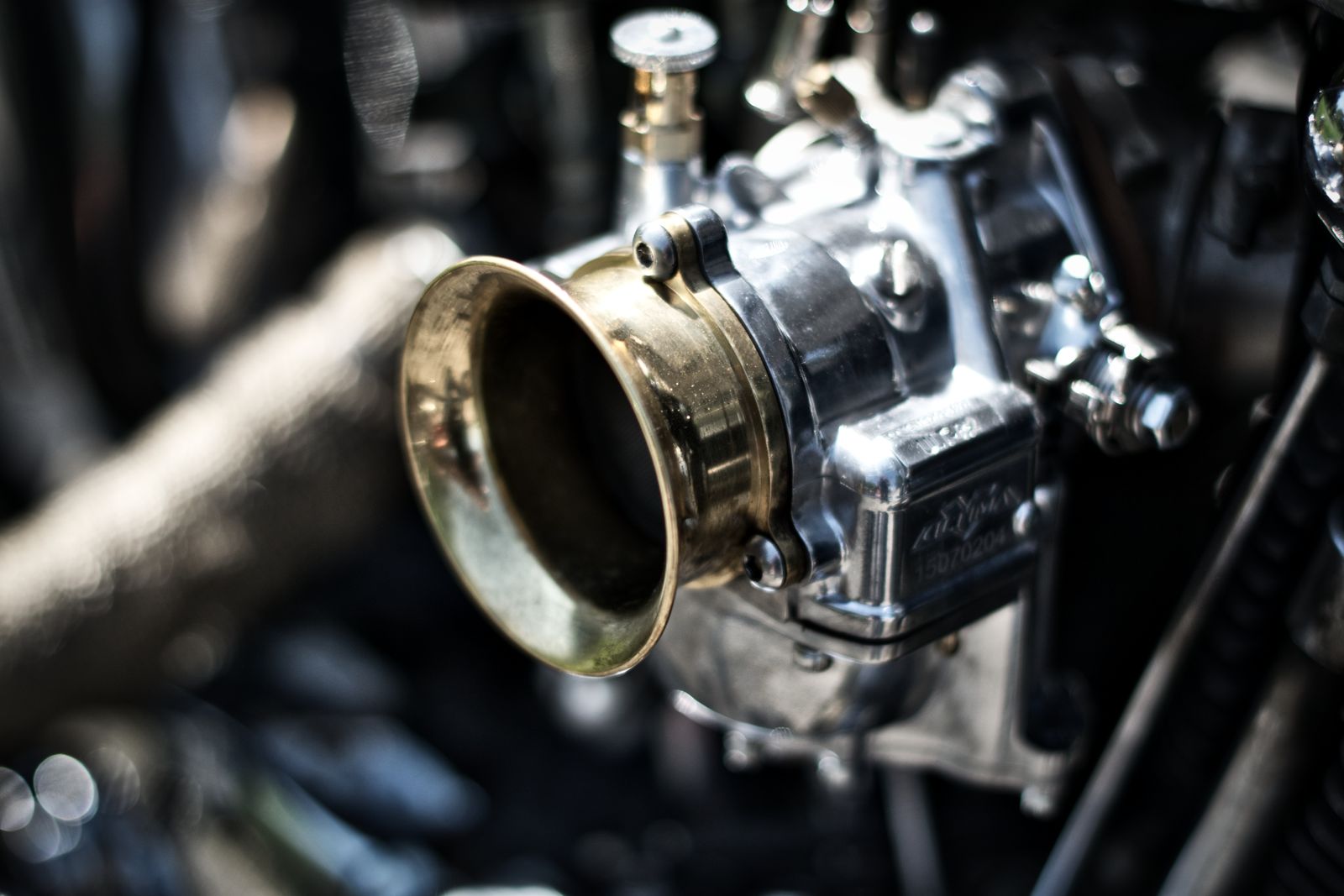 Close-up van een zilverkleurige carburateur op het blok van een Royal Enfield-motor