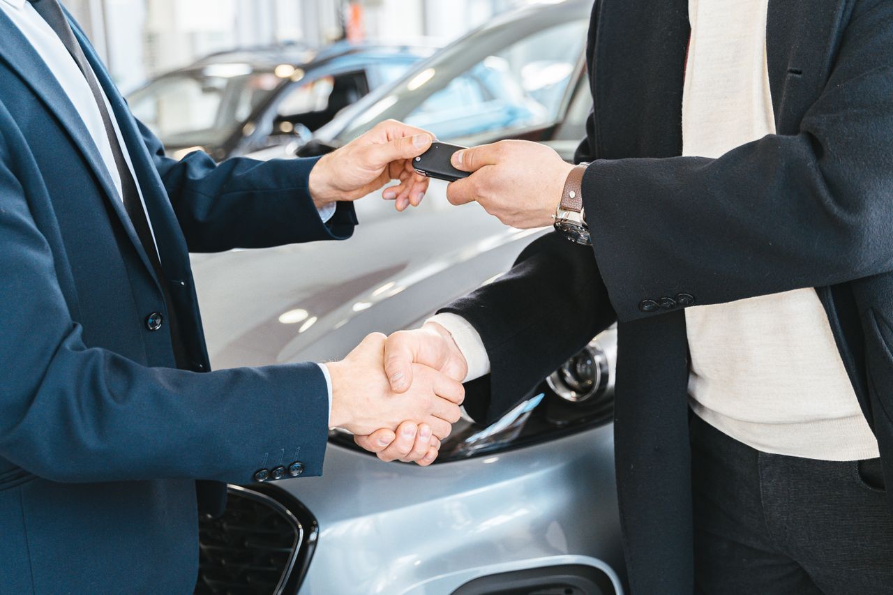 Overhandiging van autosleutels met een handdruk bij een autodealer